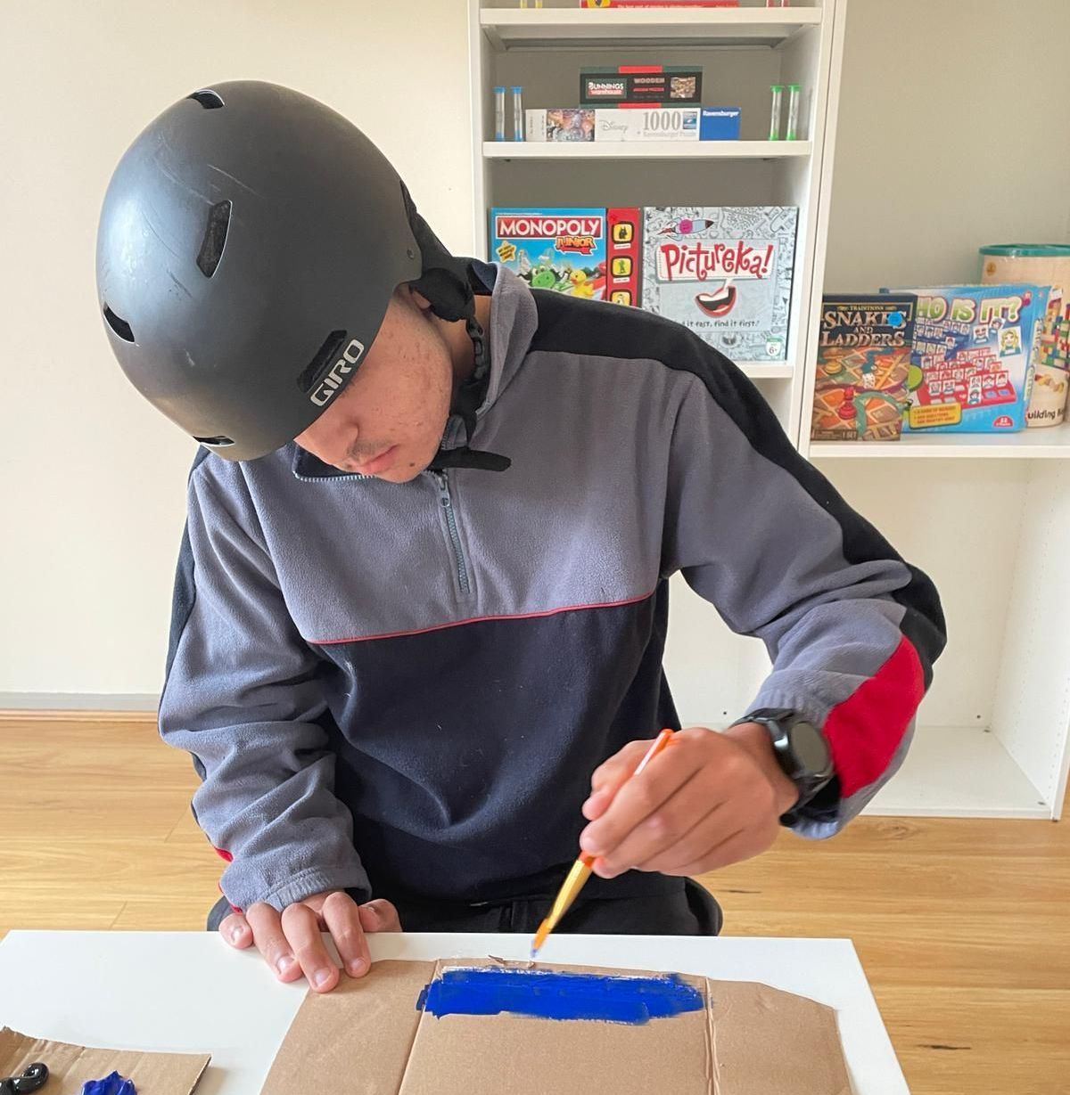 NDIS support in Gungahlin and Canberra-Wide - A man wearing a helmet is painting on a piece of cardboard