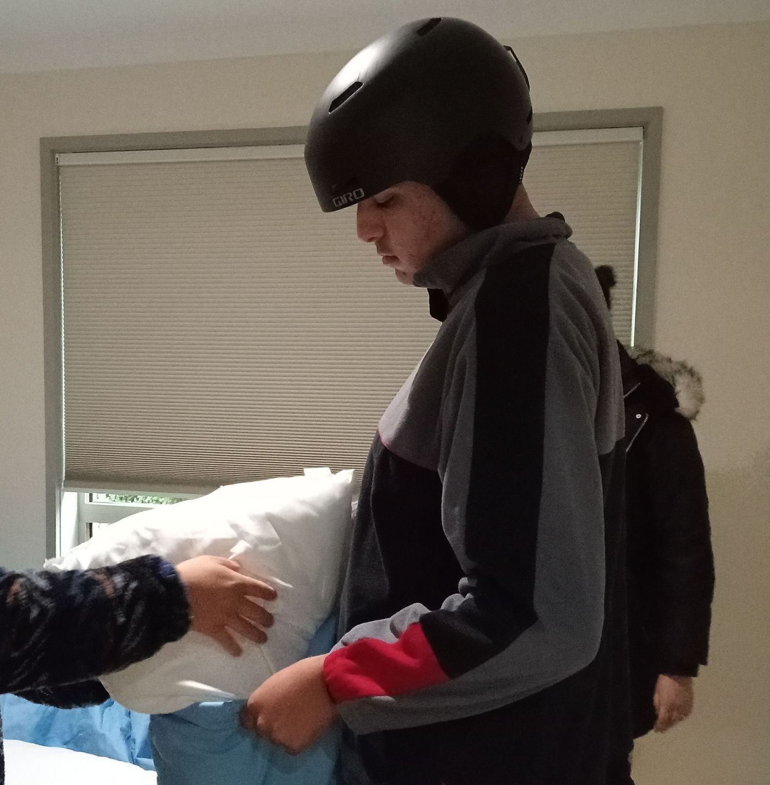 A man wearing a black helmet is holding a pillow - NDIS accomodation in Gungahlin