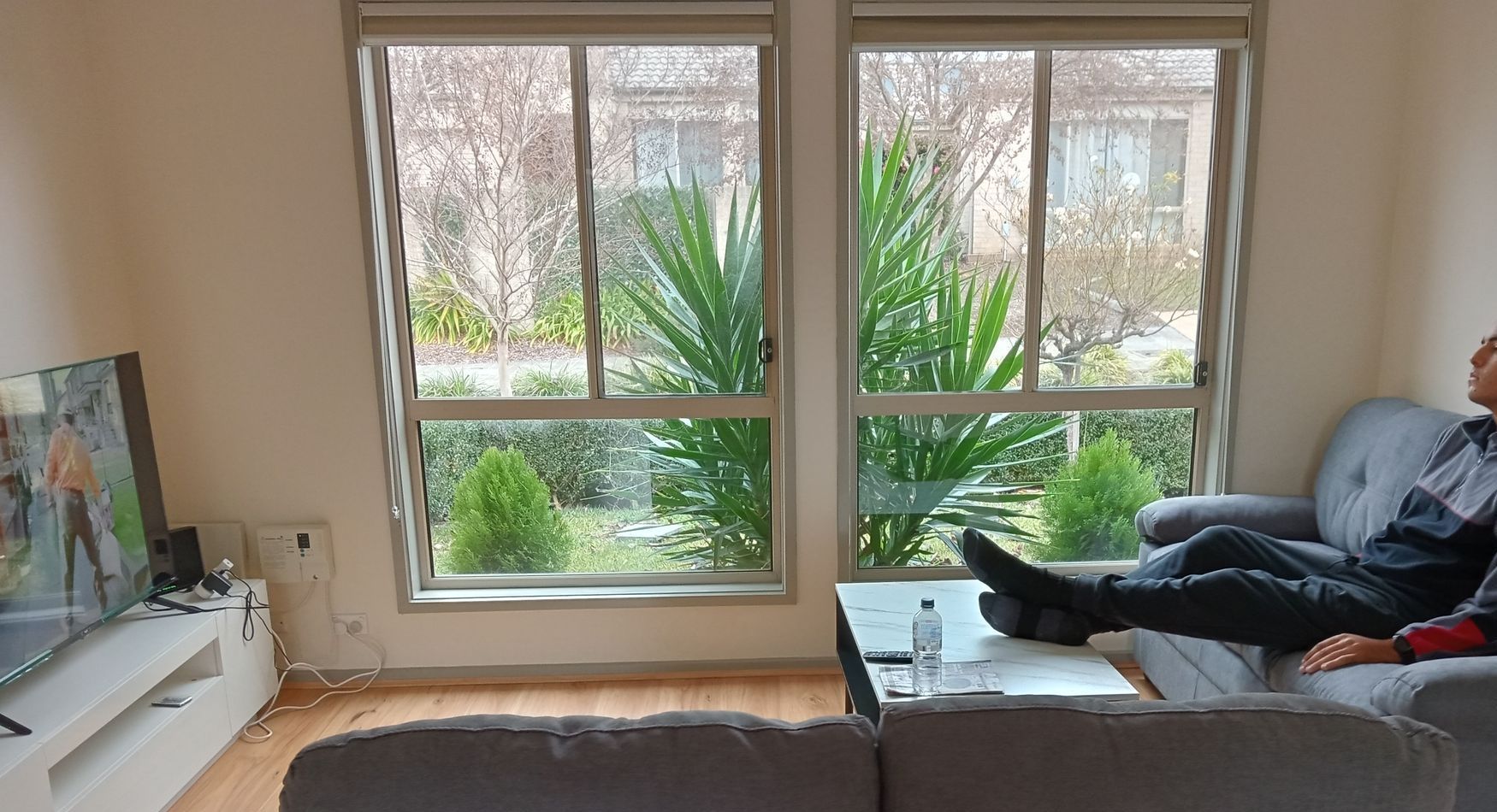 A man is sitting on a couch in a living room. SIL – Supported Independent Living, NDIS, Canberra.