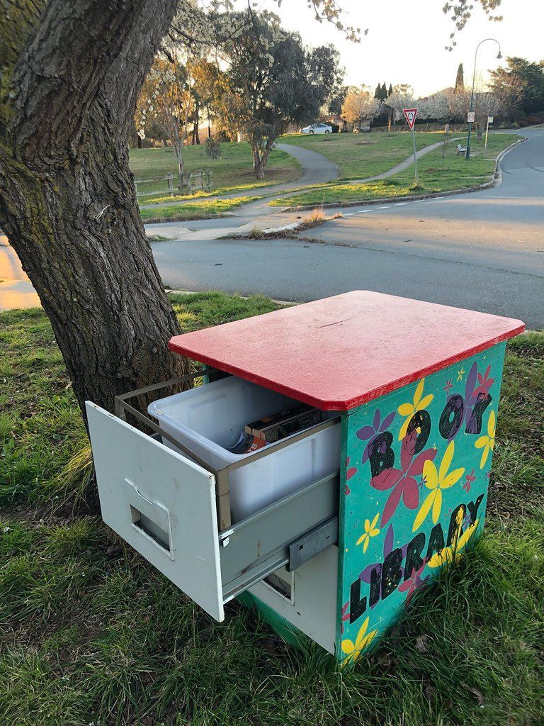 A box with a drawer open is sitting under a tree.