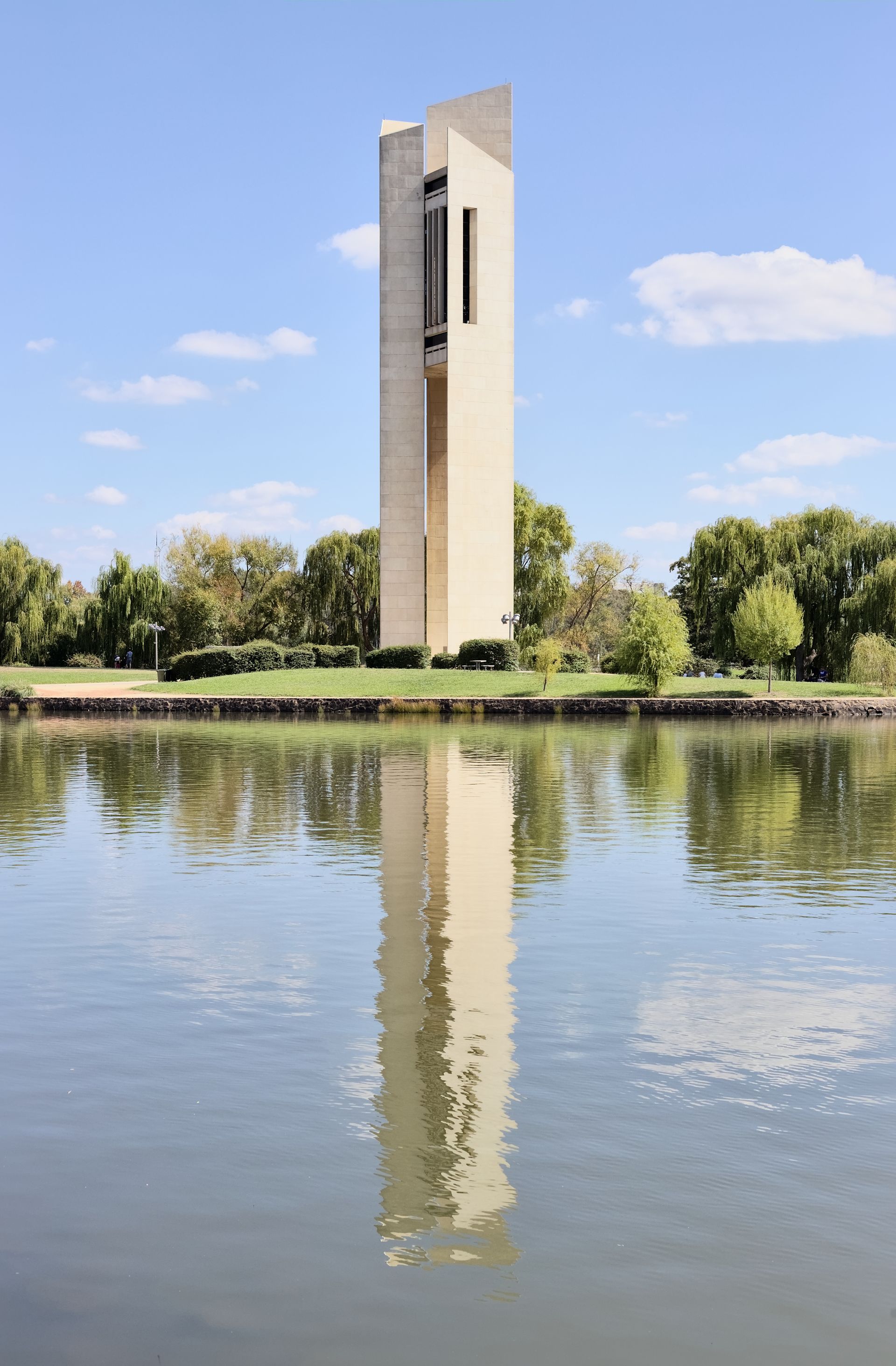 A tall building is reflected in a body of water.