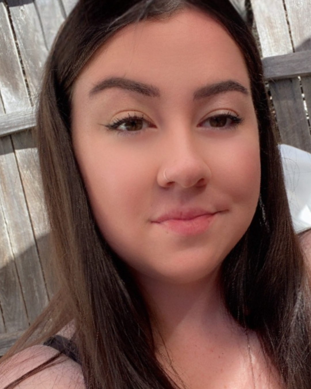 A young woman wearing a black shirt and a necklace is smiling for the camera.