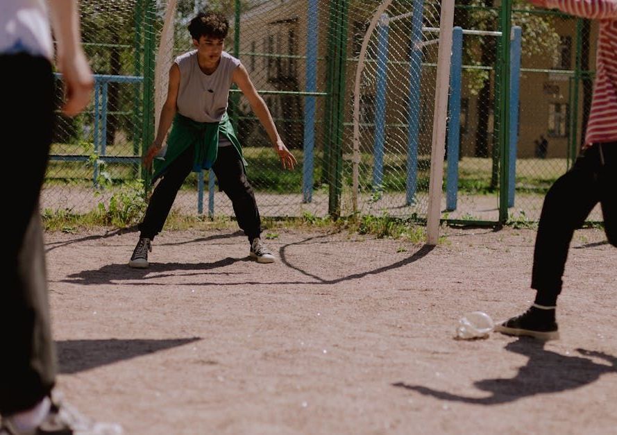 A group of people are playing soccer on a dirt field.