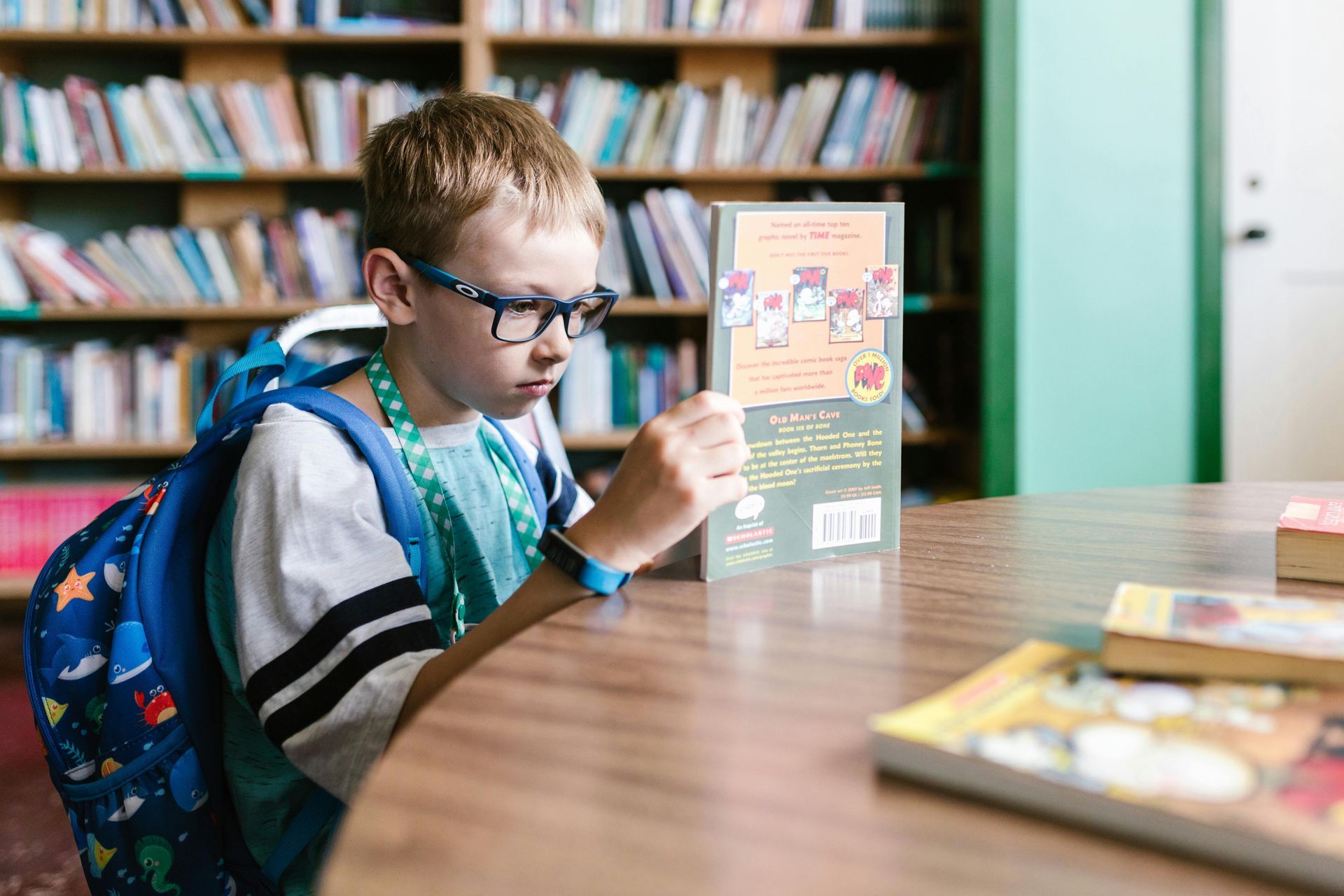 A young boy is reading a book in a library. SIL – Supported Independent Living, NDIS, Canberra