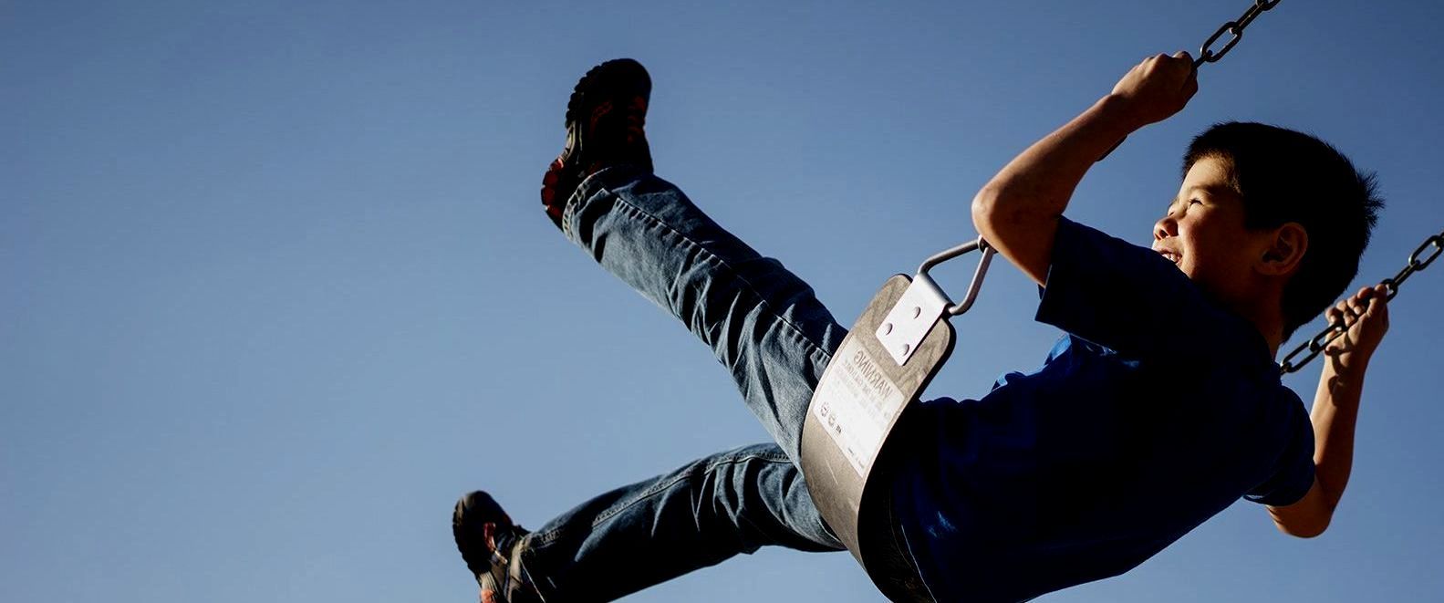 SIL – Supported Independent Living, NDIS, Canberra. A young boy is flying through the air on a swing.