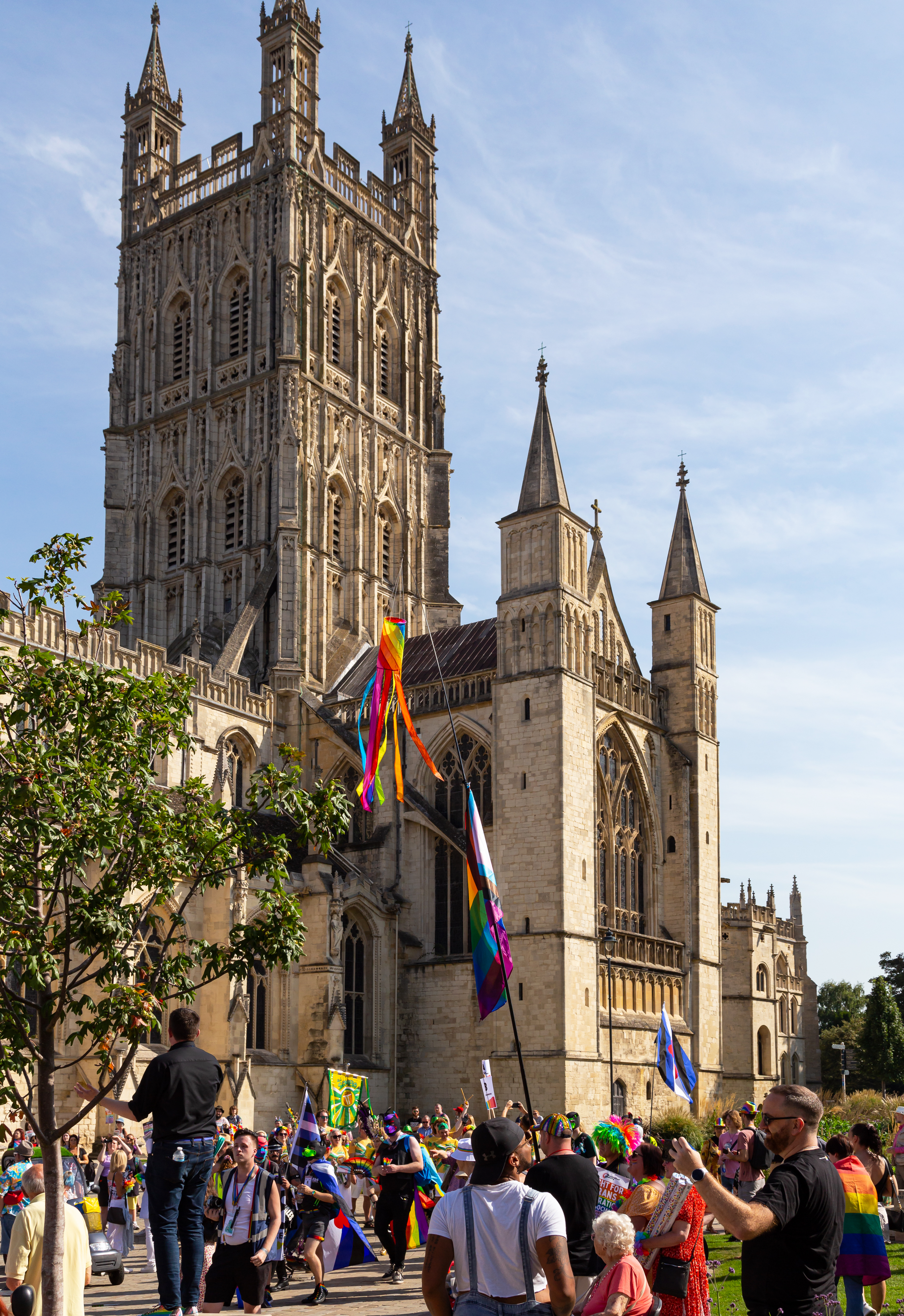 Photo outside Gloucester Cathedral of a group of people forming for the Pride in Gloucestershire 2023 March.