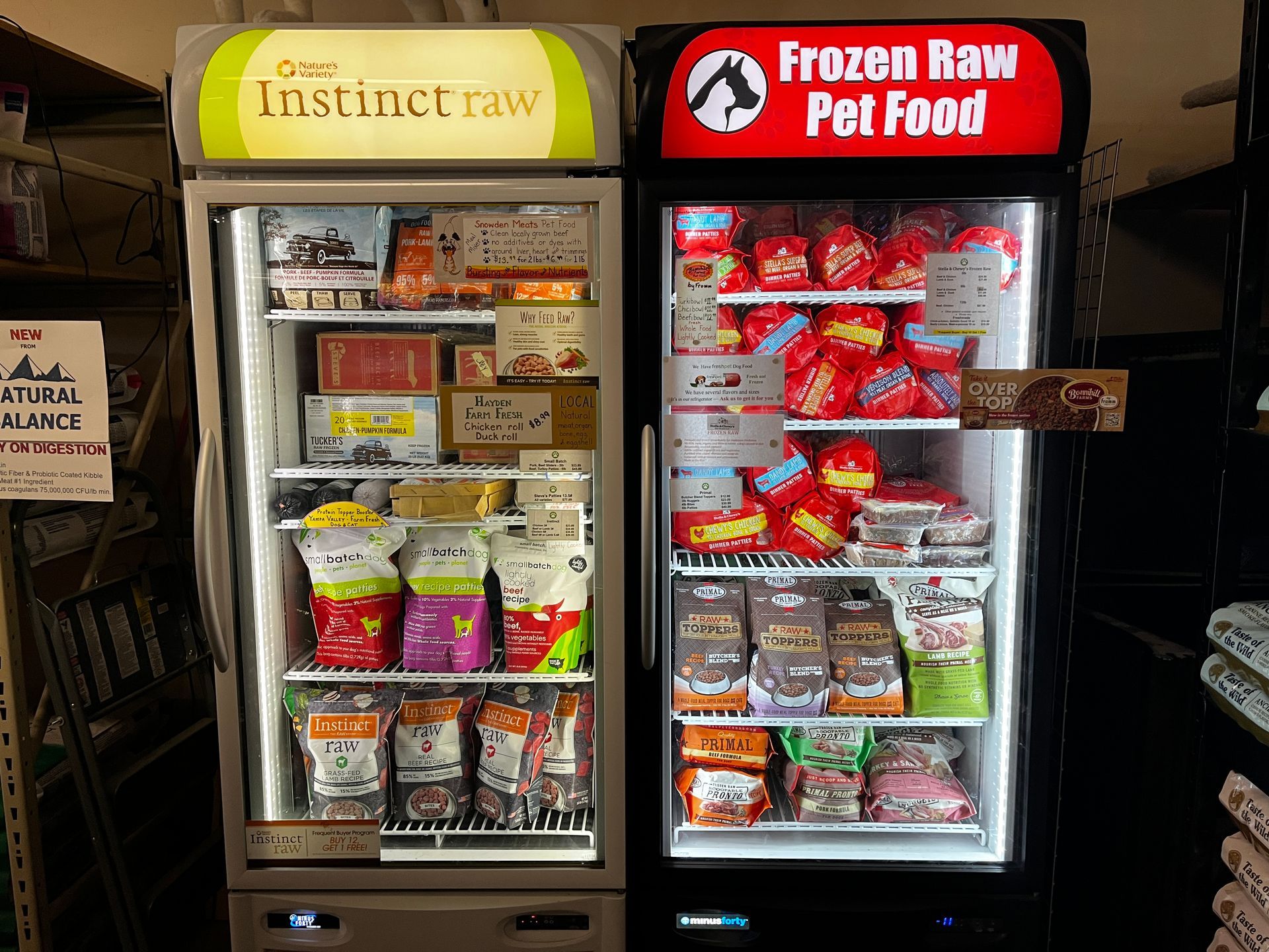 Two refrigerators filled with frozen raw pet food in a store.