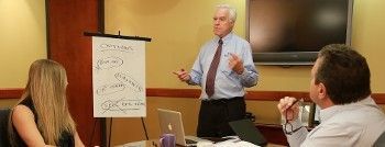 Man giving presentation with flip chart to a small group in a meeting room.