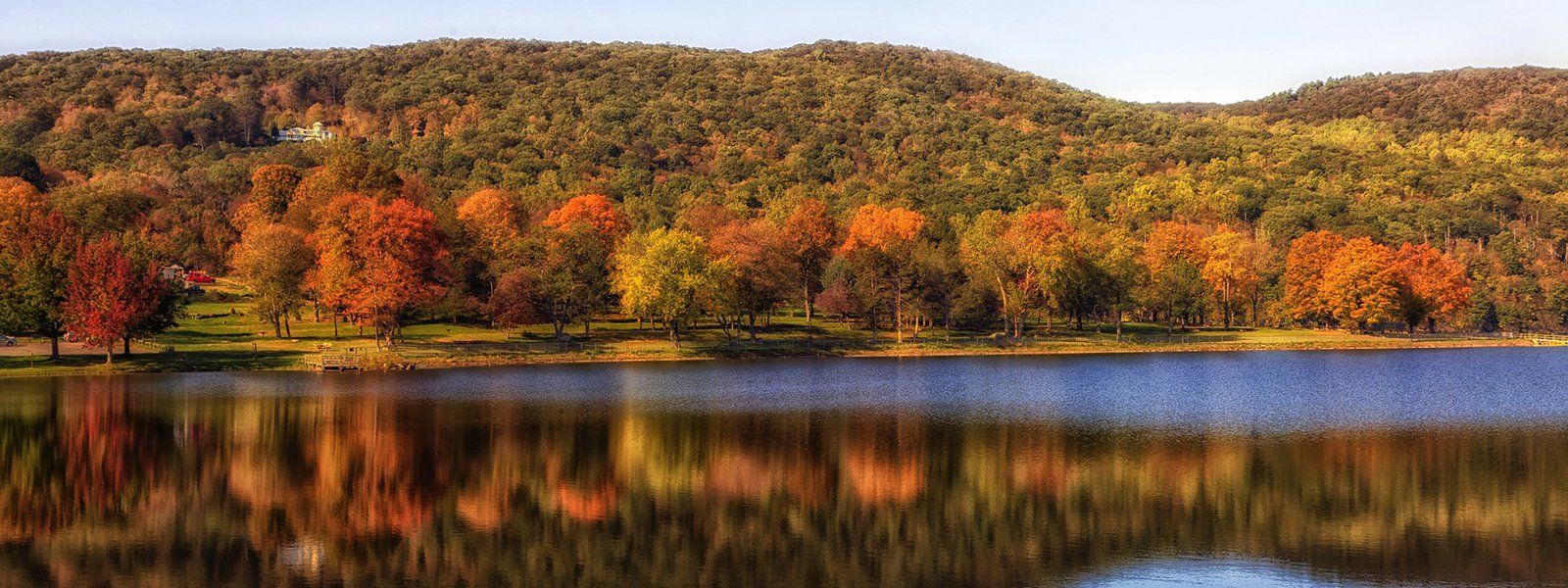 There is a lake in the middle of a forest with trees reflected in the water.