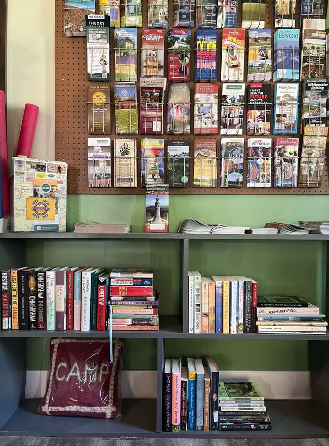 A shelf filled with books and a pillow that says camp