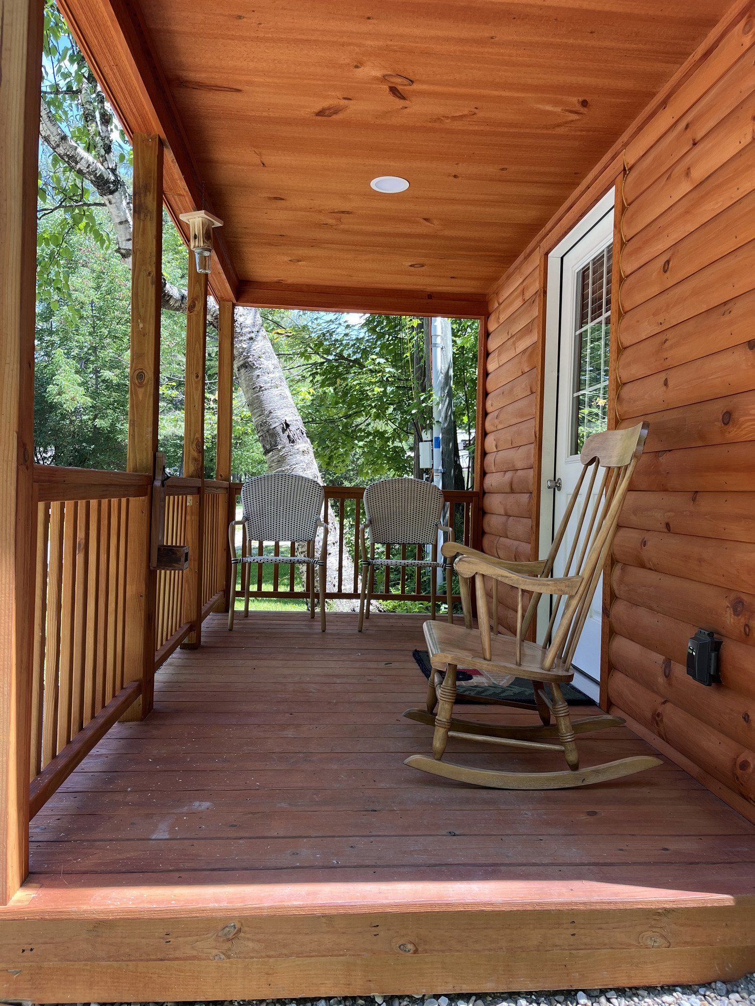 A wooden porch with a rocking chair and chairs on it