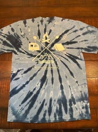 A blue tie dye t-shirt is sitting on a wooden table.