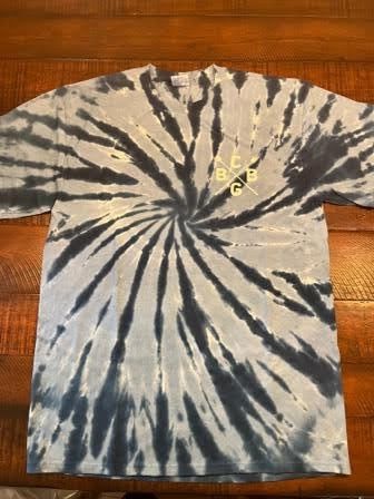 A tie dye t-shirt is sitting on a wooden table.