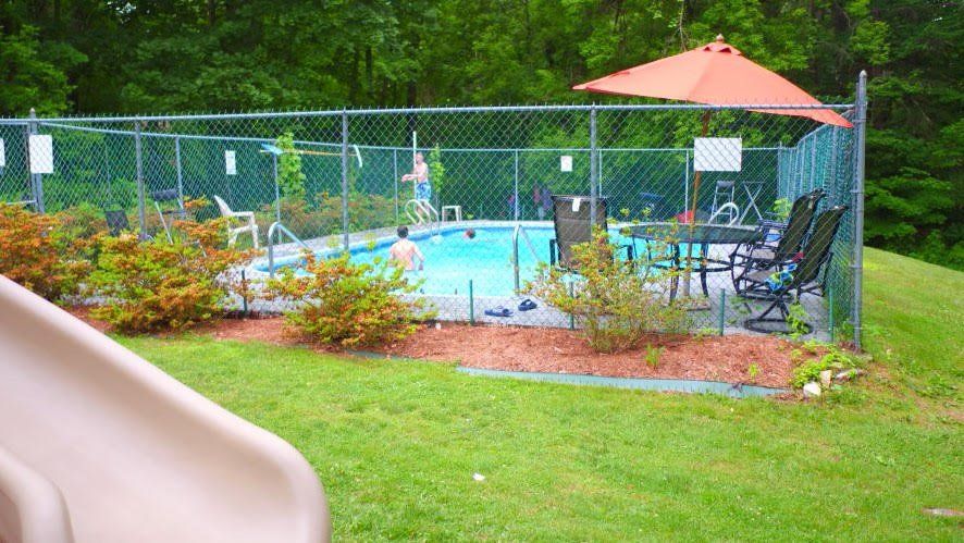 A fenced in backyard with a swimming pool and umbrellas