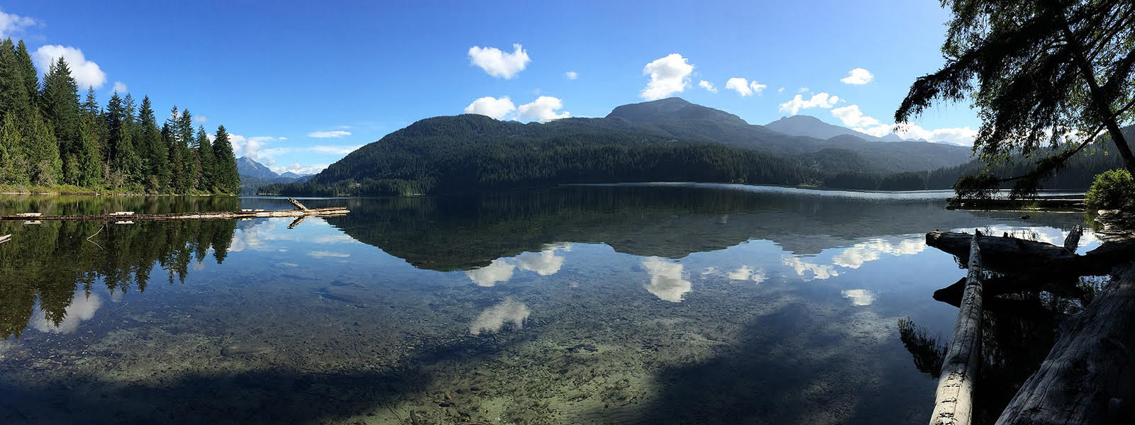 A lake with mountains in the background and trees on the shore.