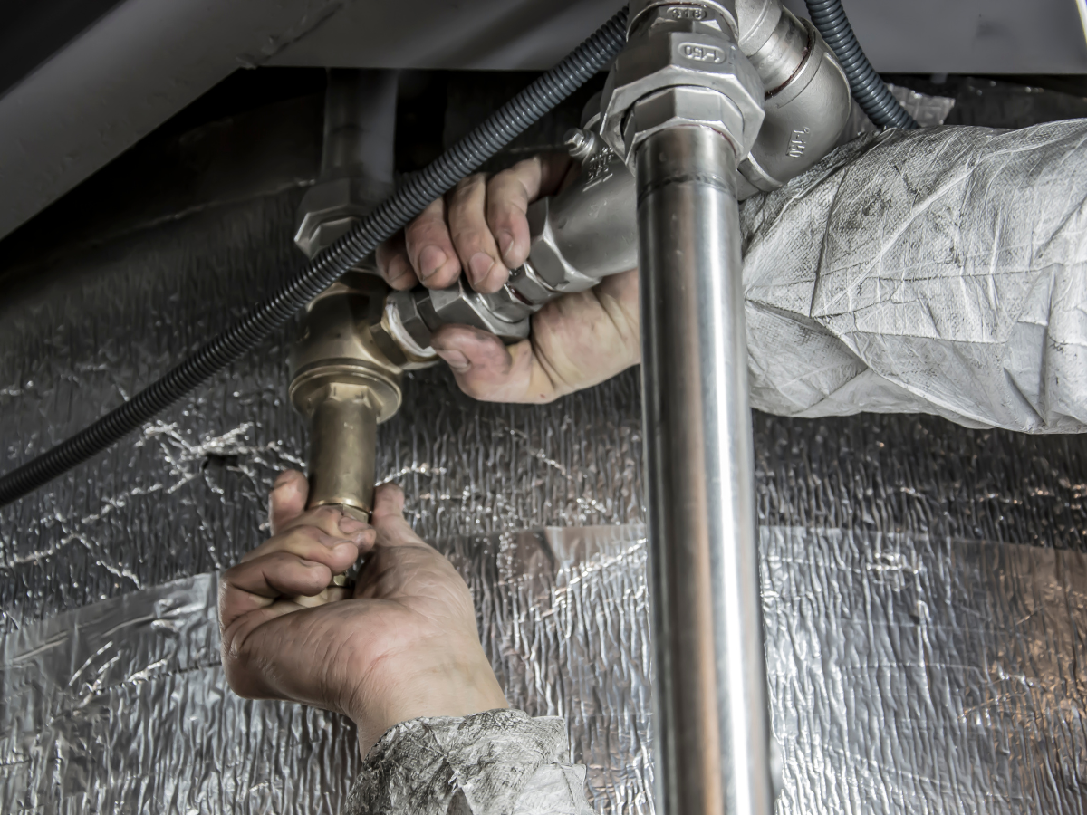 A person is fixing a pipe under a sink.