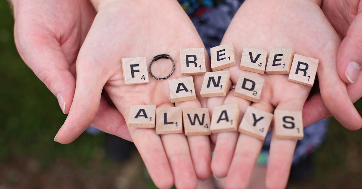 A person is holding scrabble tiles in their hands that say forever and always