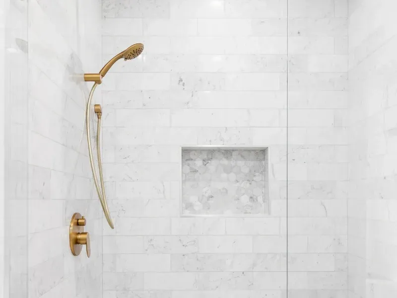 RSG Custom Builds shower remodel and install in Seattle, WA with a gold shower head and a marble wall. Ideas and inspiration.
