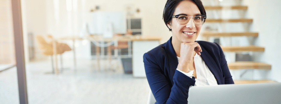 A woman is sitting at a desk in front of a laptop computer.