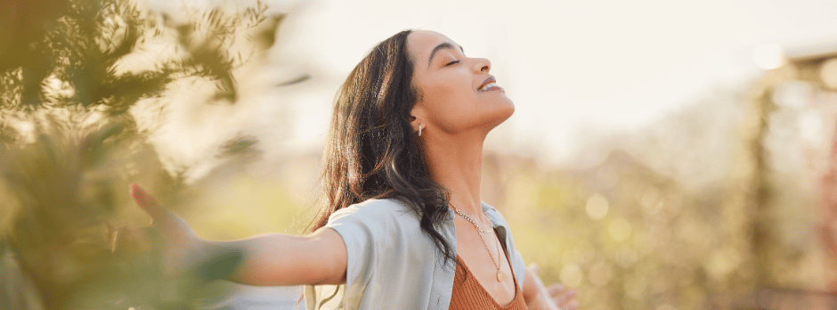 A woman is standing in a field with her arms outstretched.