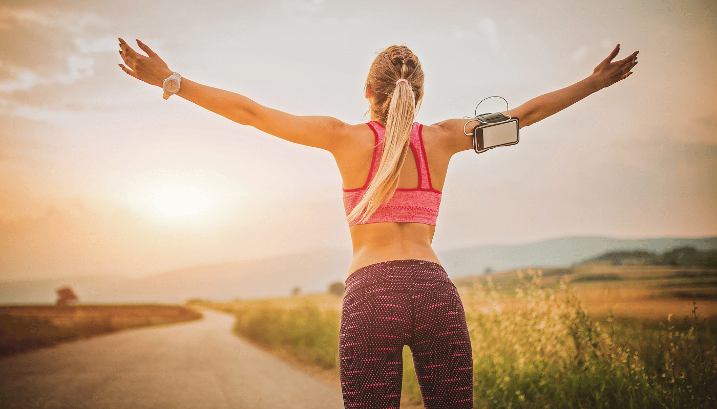 A woman is standing on a road with her arms outstretched.