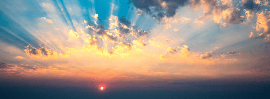 The sun is shining through the clouds at sunrise.