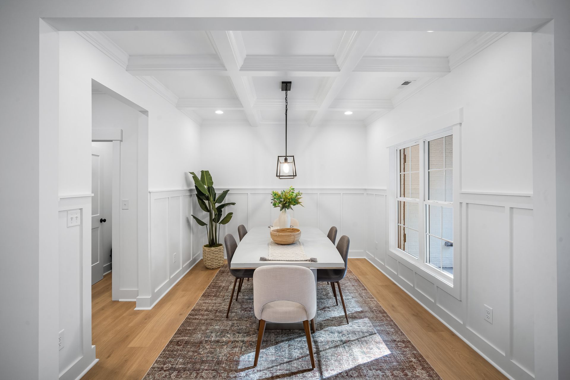 A dining room with a long table and chairs and a rug.