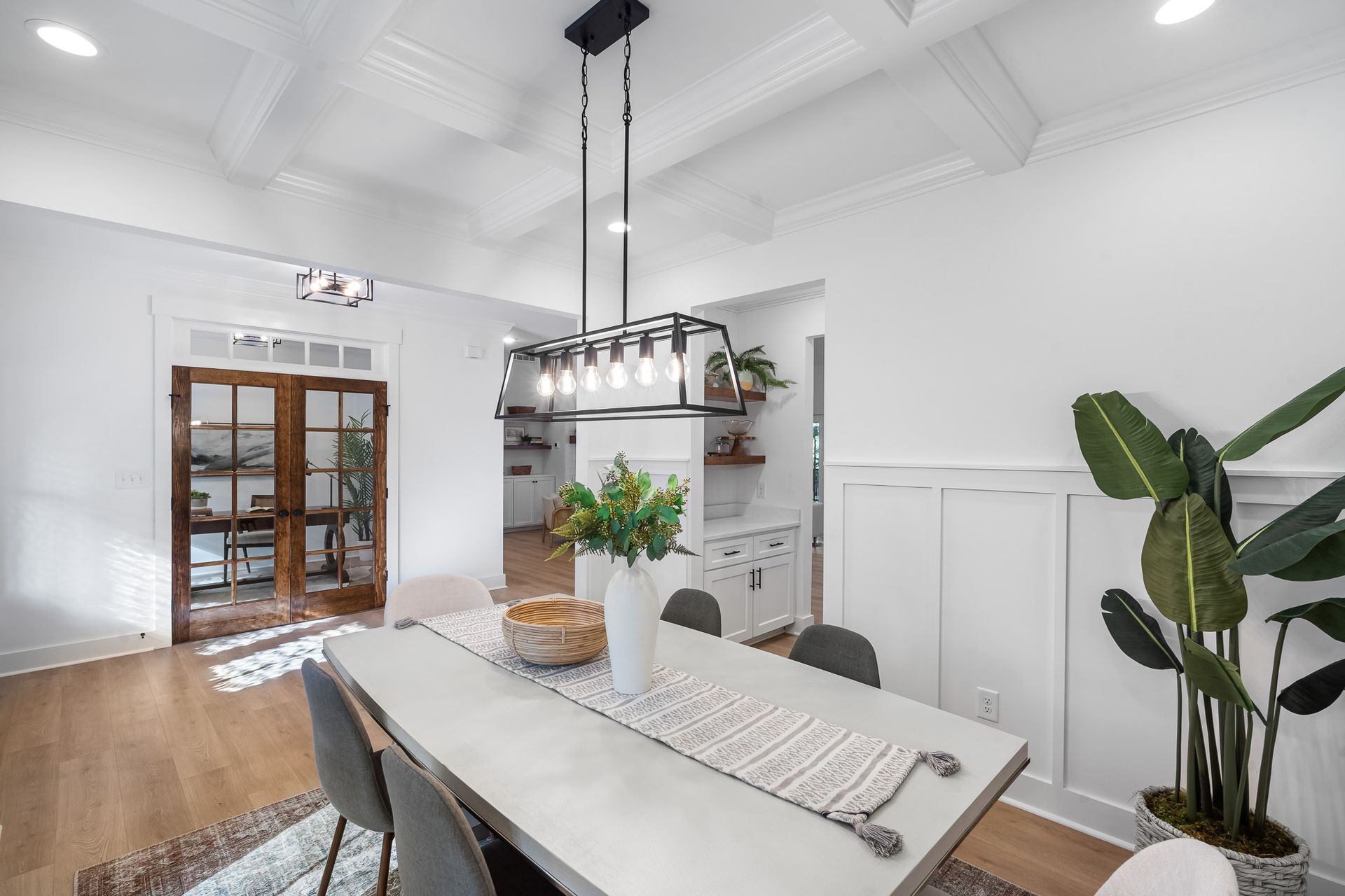 A dining room with a table and chairs and a chandelier hanging from the ceiling.