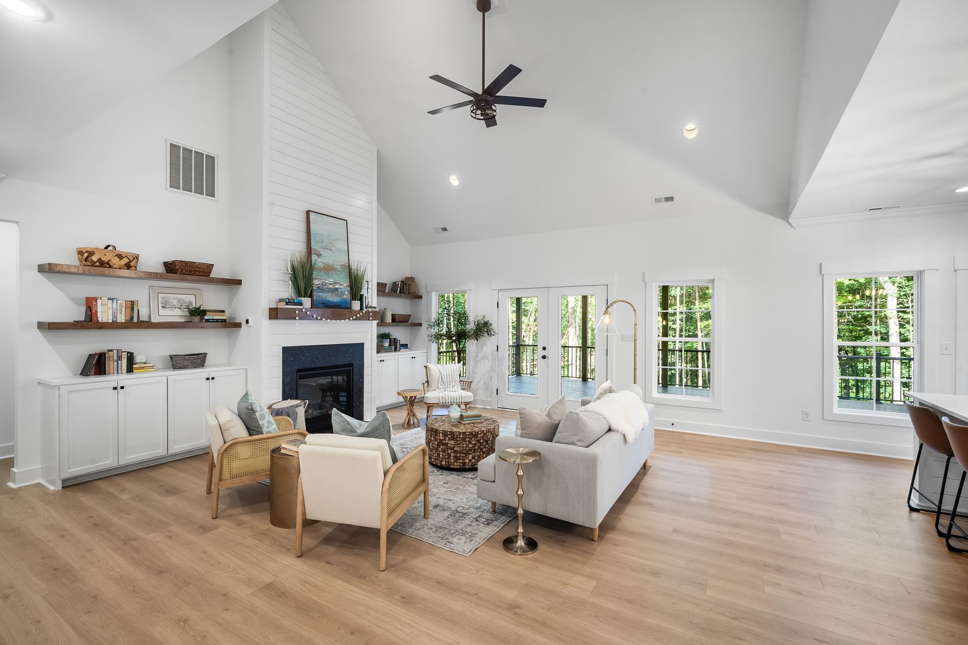 A living room with a couch , chairs , a fireplace and a ceiling fan.