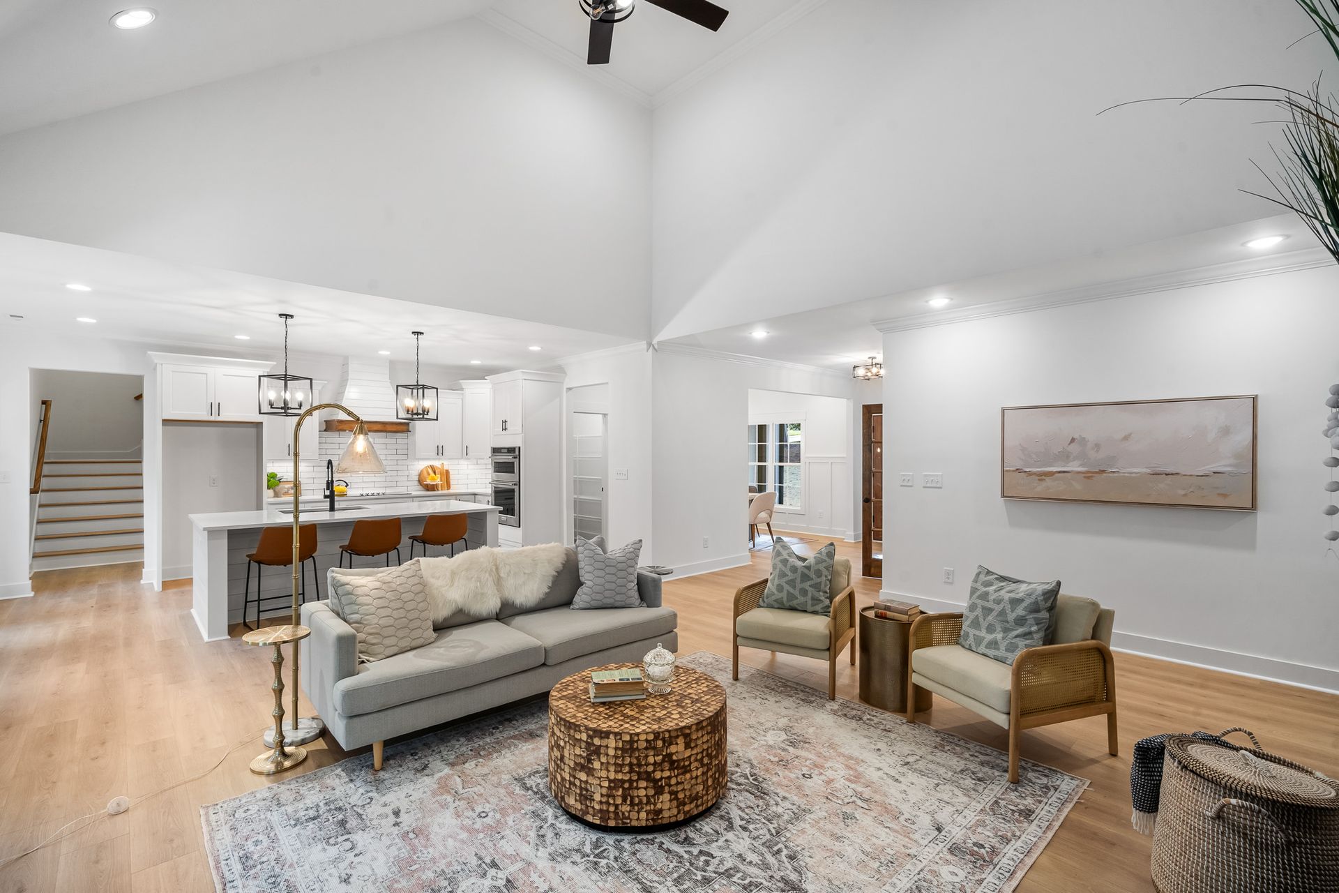 A living room with a couch , chairs , a table and a ceiling fan.