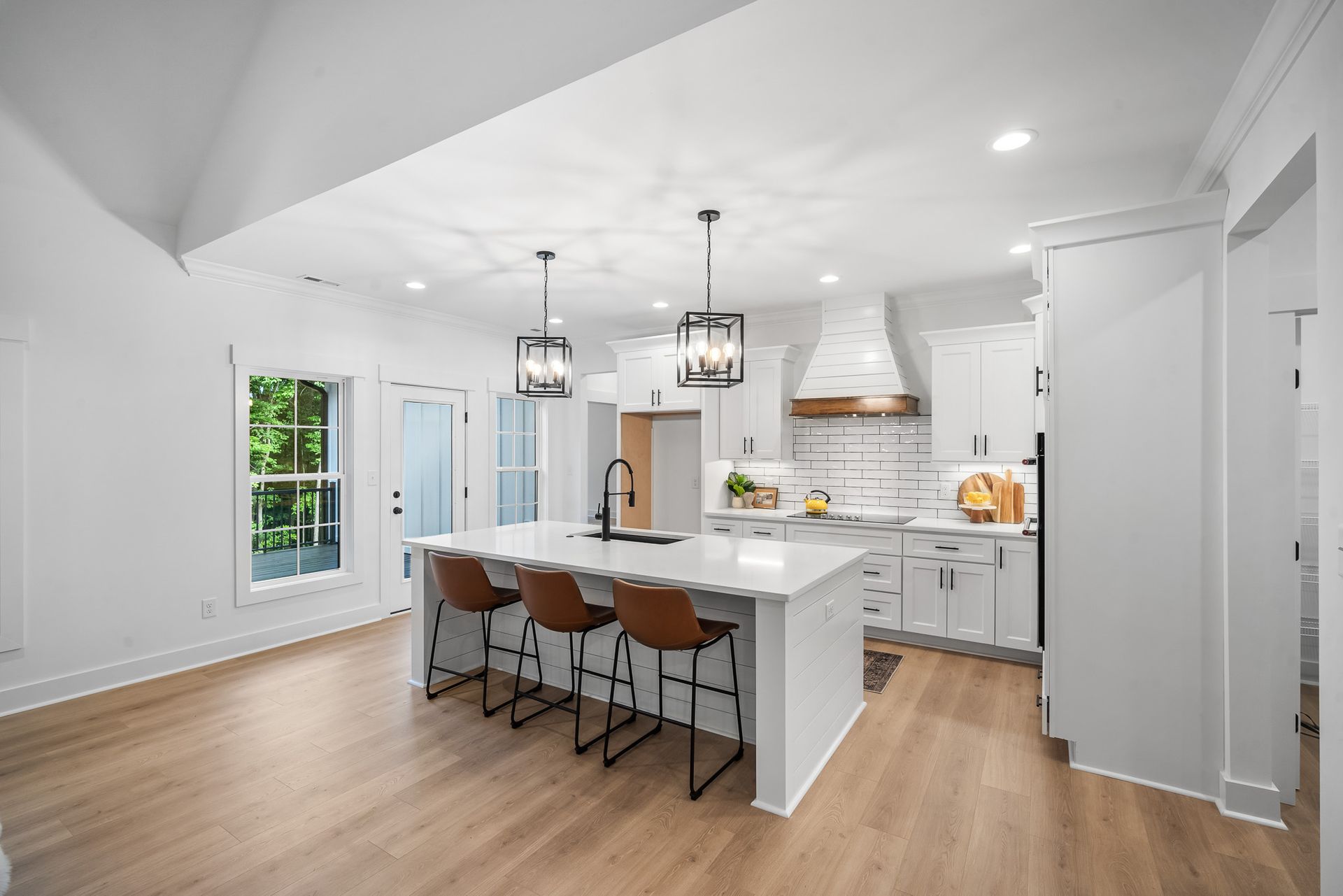 A kitchen with white cabinets , a large island , and wooden floors.