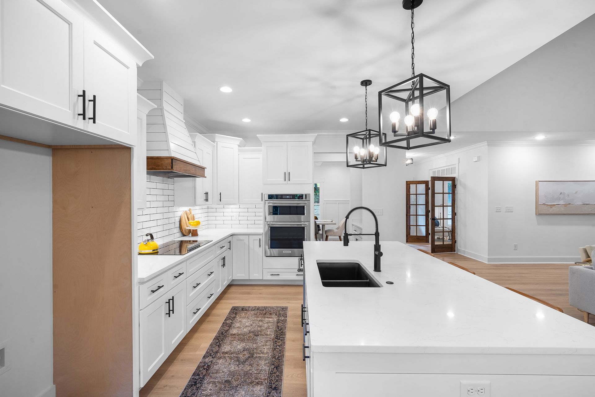 A kitchen with white cabinets , white counter tops , a sink , and a rug.