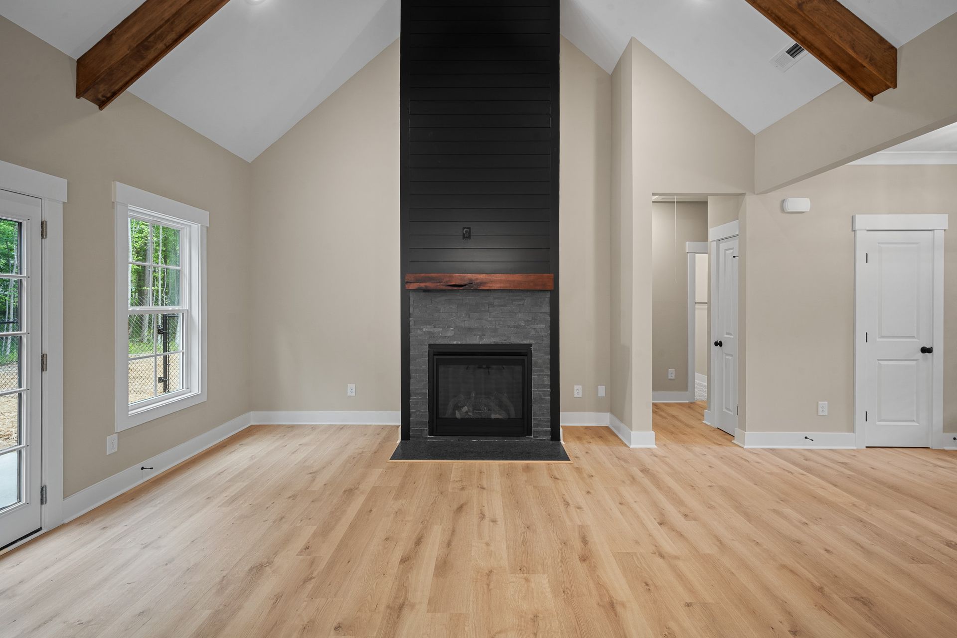 An empty living room with hardwood floors and a fireplace.