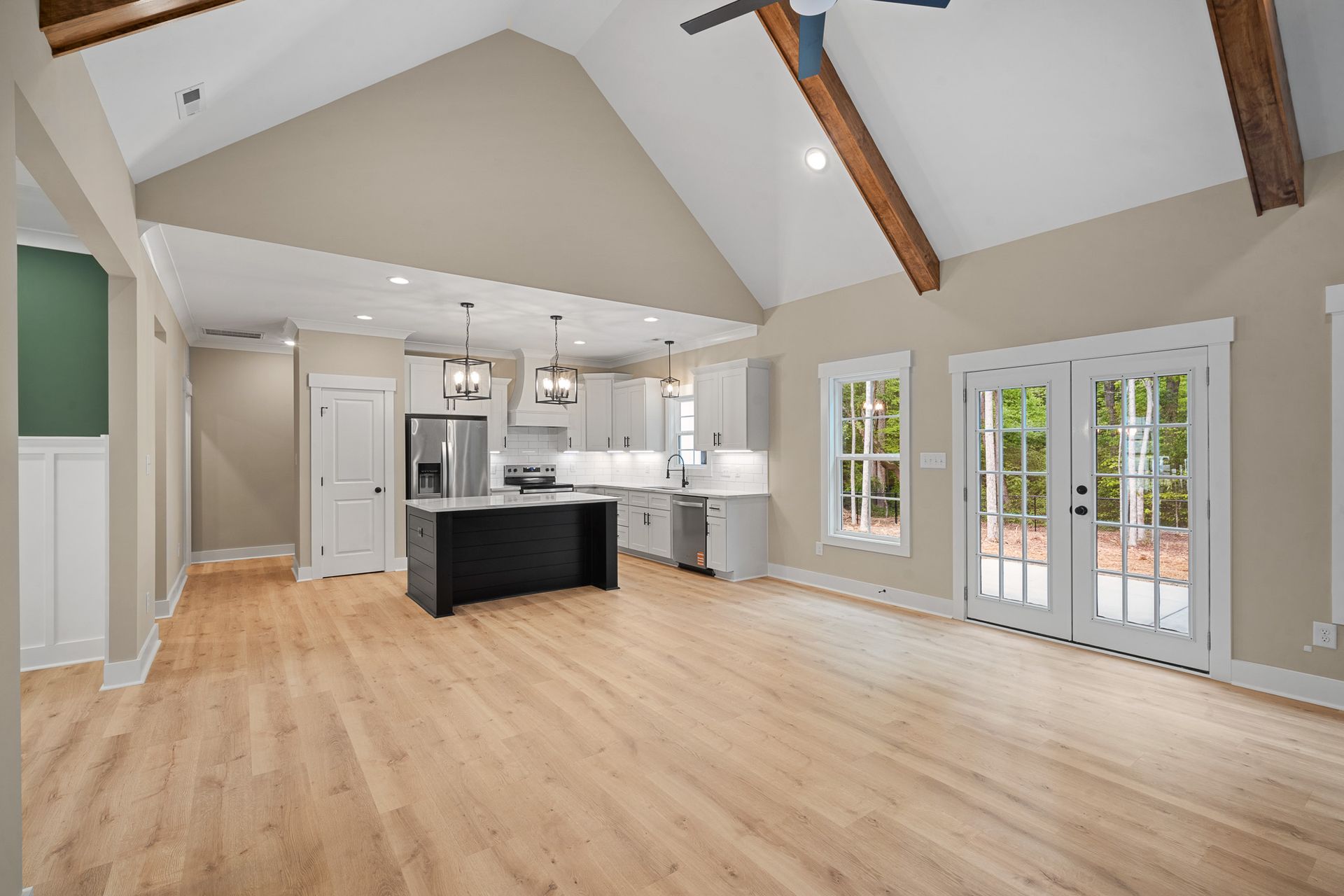 A kitchen and living room in a house with hardwood floors and a vaulted ceiling.