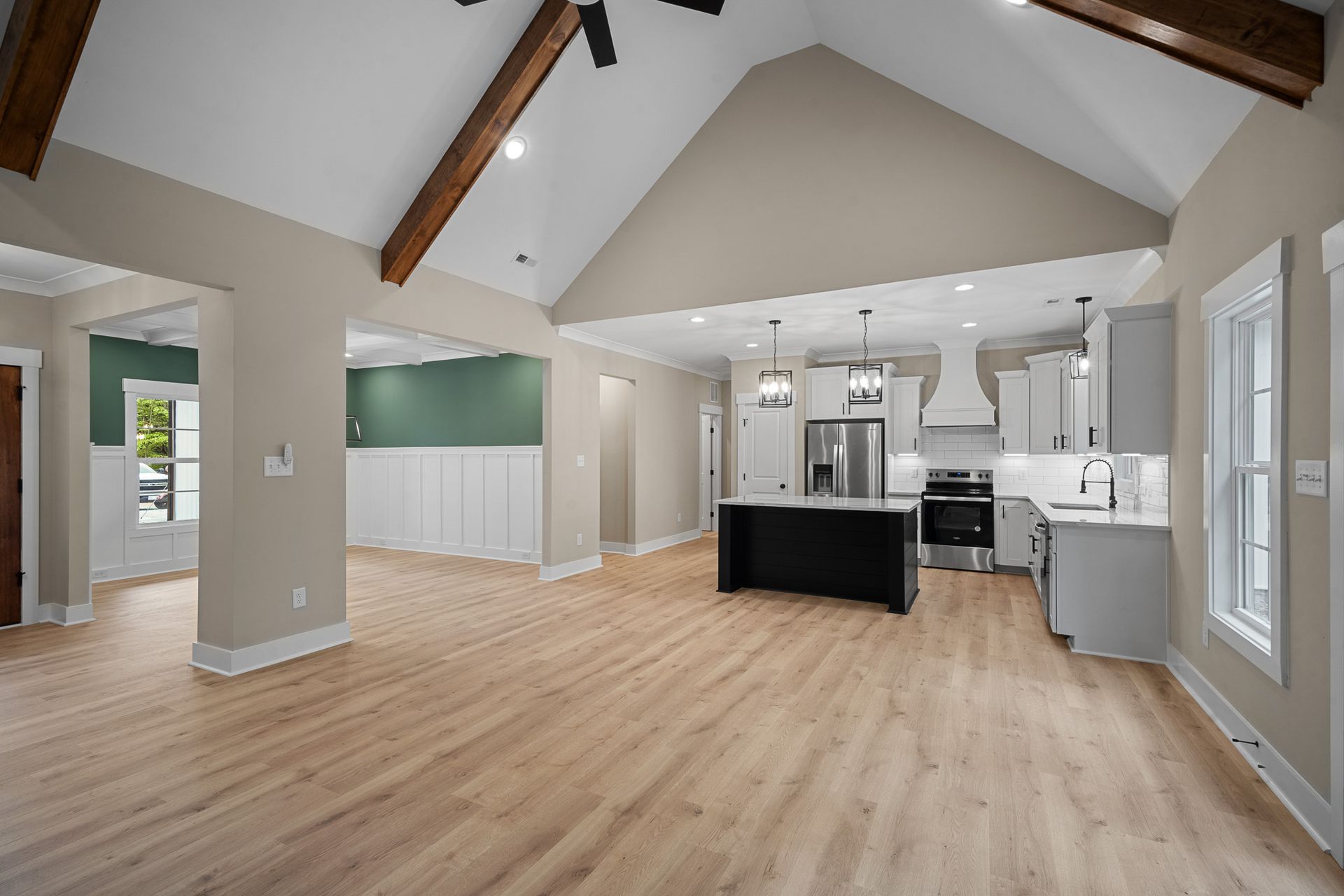 A kitchen and living room in a house with hardwood floors and a vaulted ceiling.