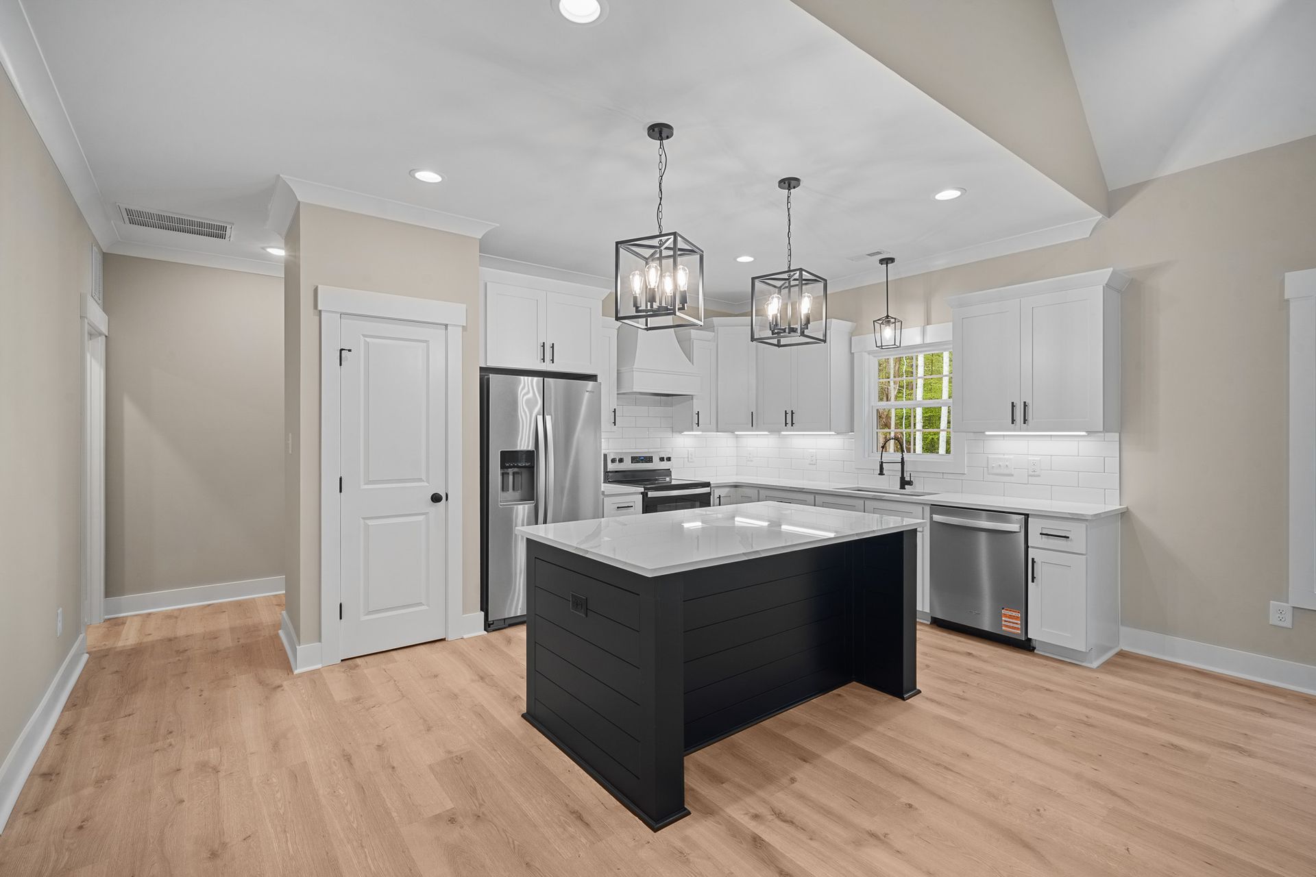 A kitchen with white cabinets , stainless steel appliances , and a large island.