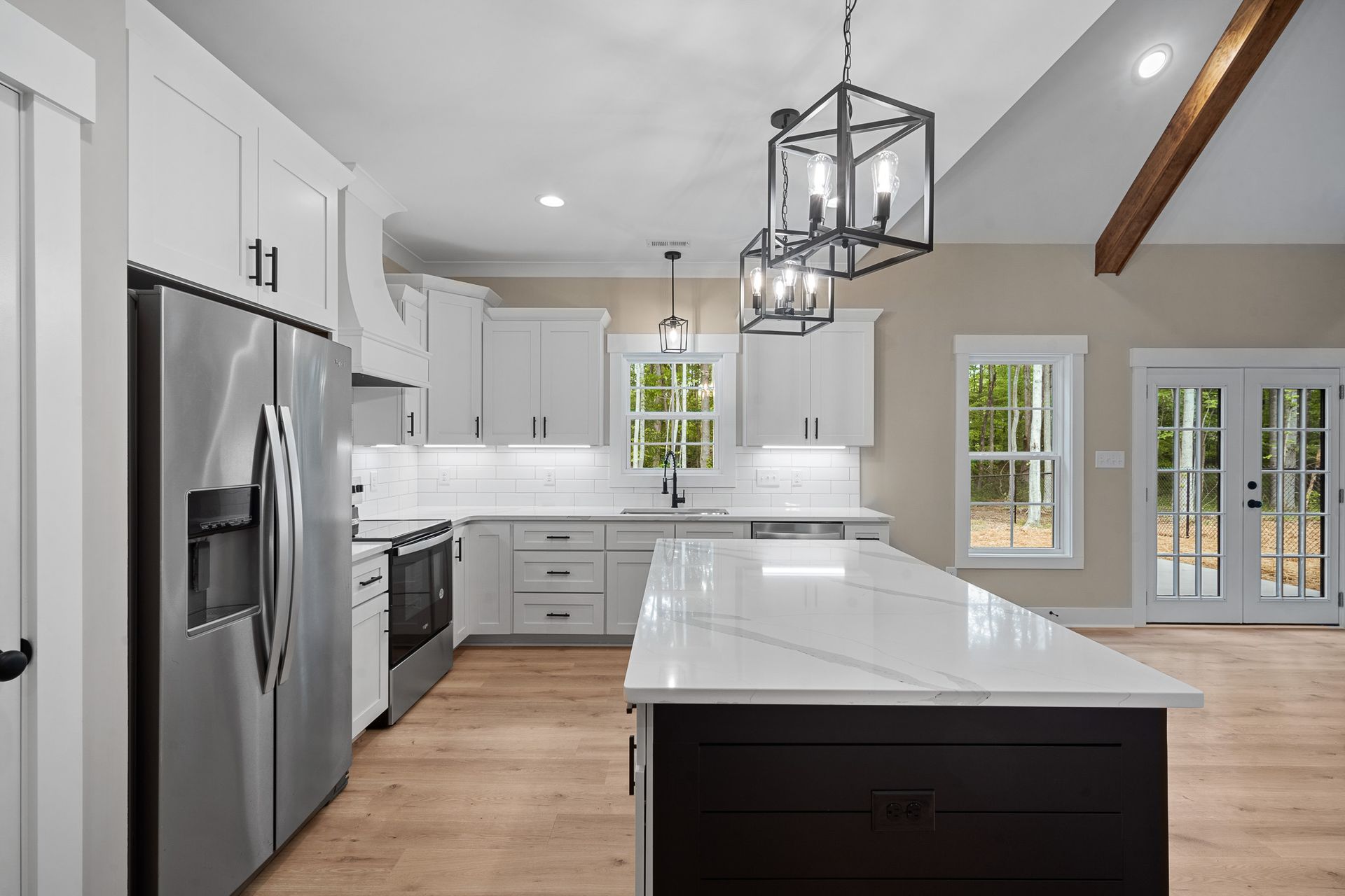 A kitchen with white cabinets , stainless steel appliances , and a large island.