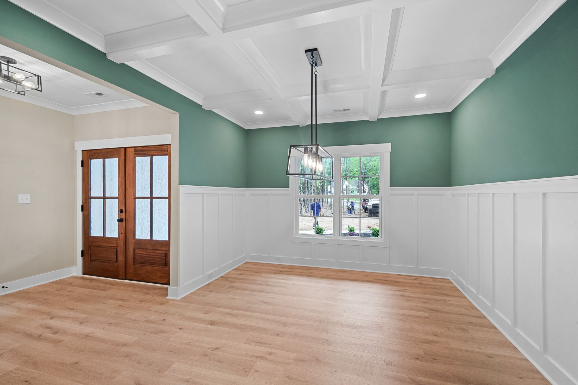 An empty dining room with green walls and wooden floors.