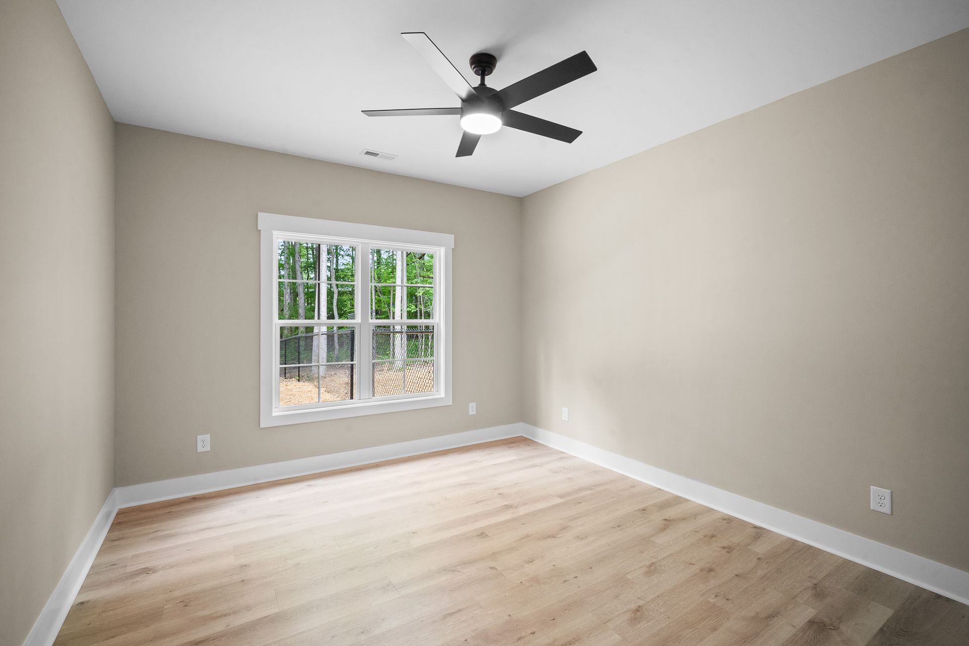 An empty room with a ceiling fan and a window.