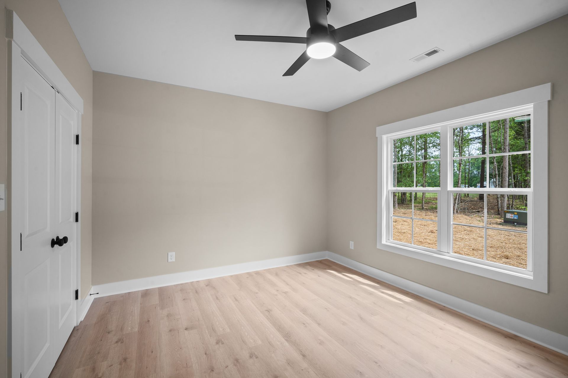 An empty bedroom with a ceiling fan and two windows.