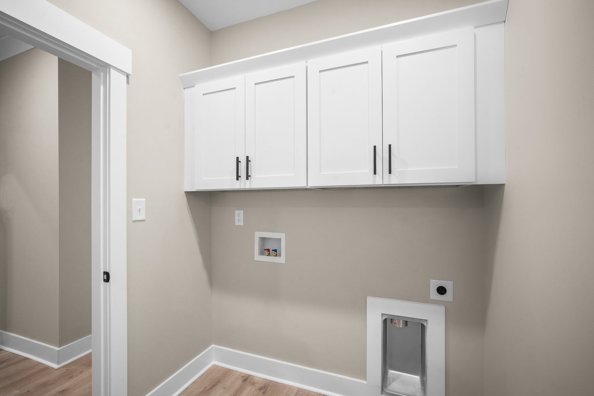 A laundry room with white cabinets and a dog door.