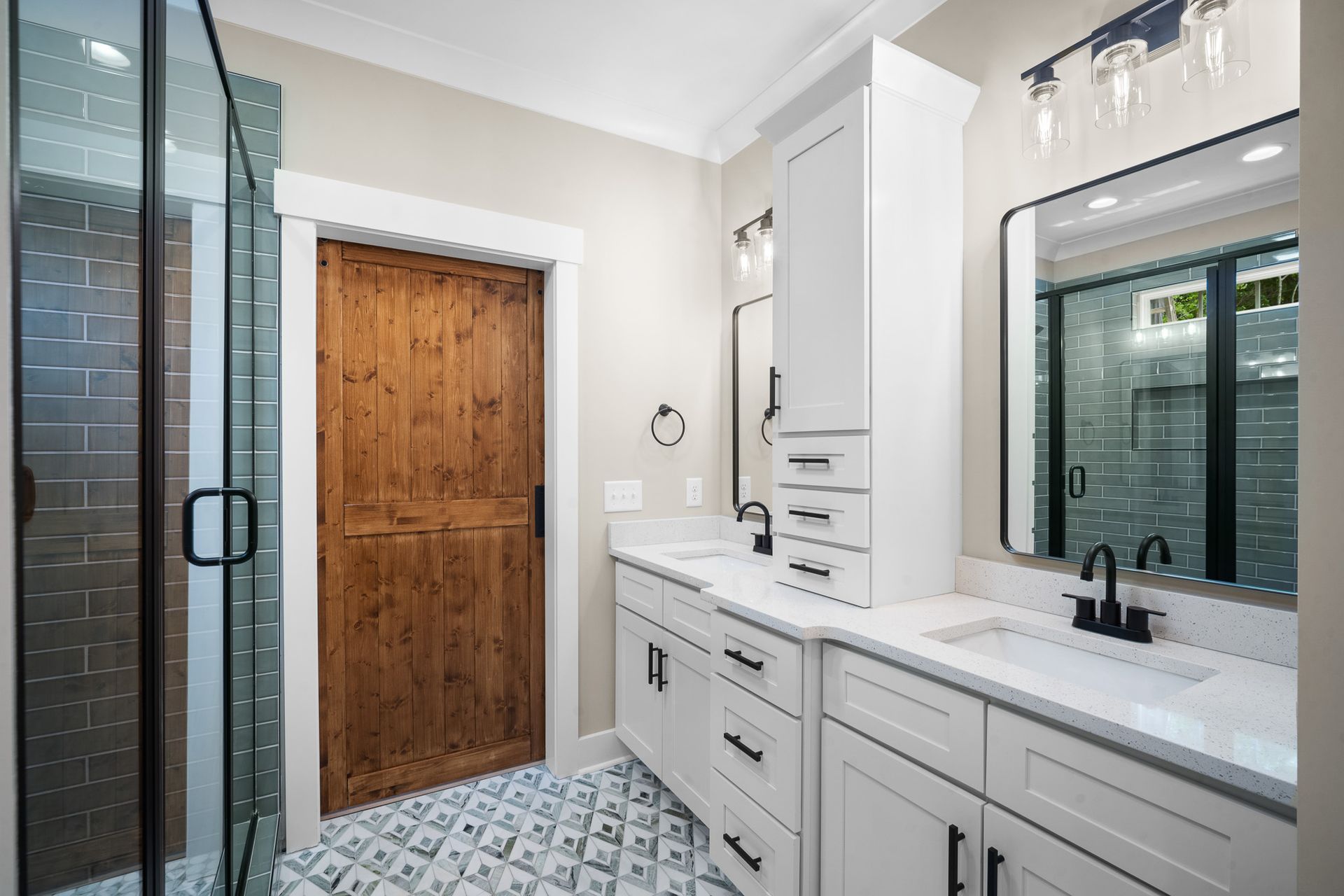 A bathroom with two sinks , a mirror and a walk in shower.