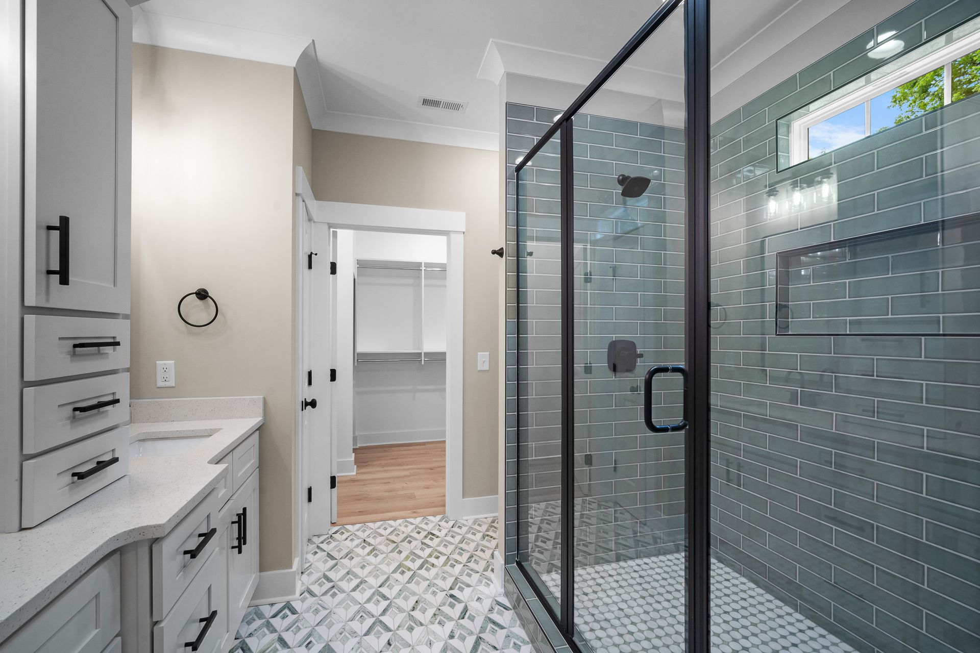 A bathroom with a walk in shower and a sink.