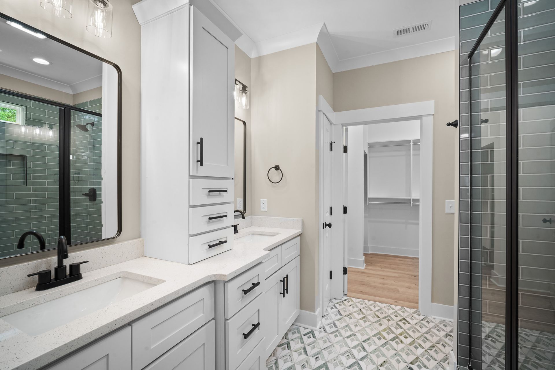 A bathroom with two sinks and a walk in shower.