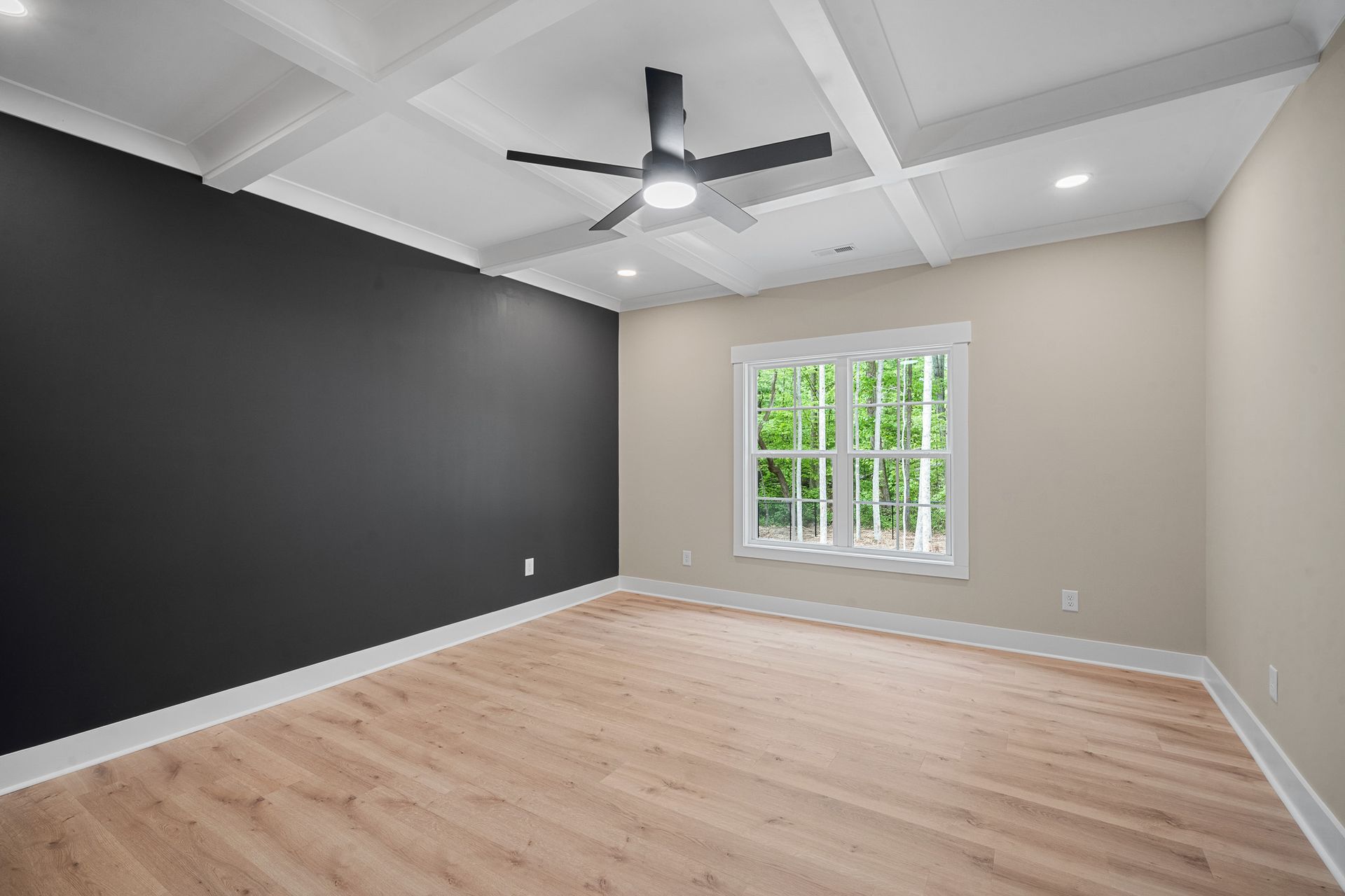An empty room with hardwood floors and a ceiling fan.