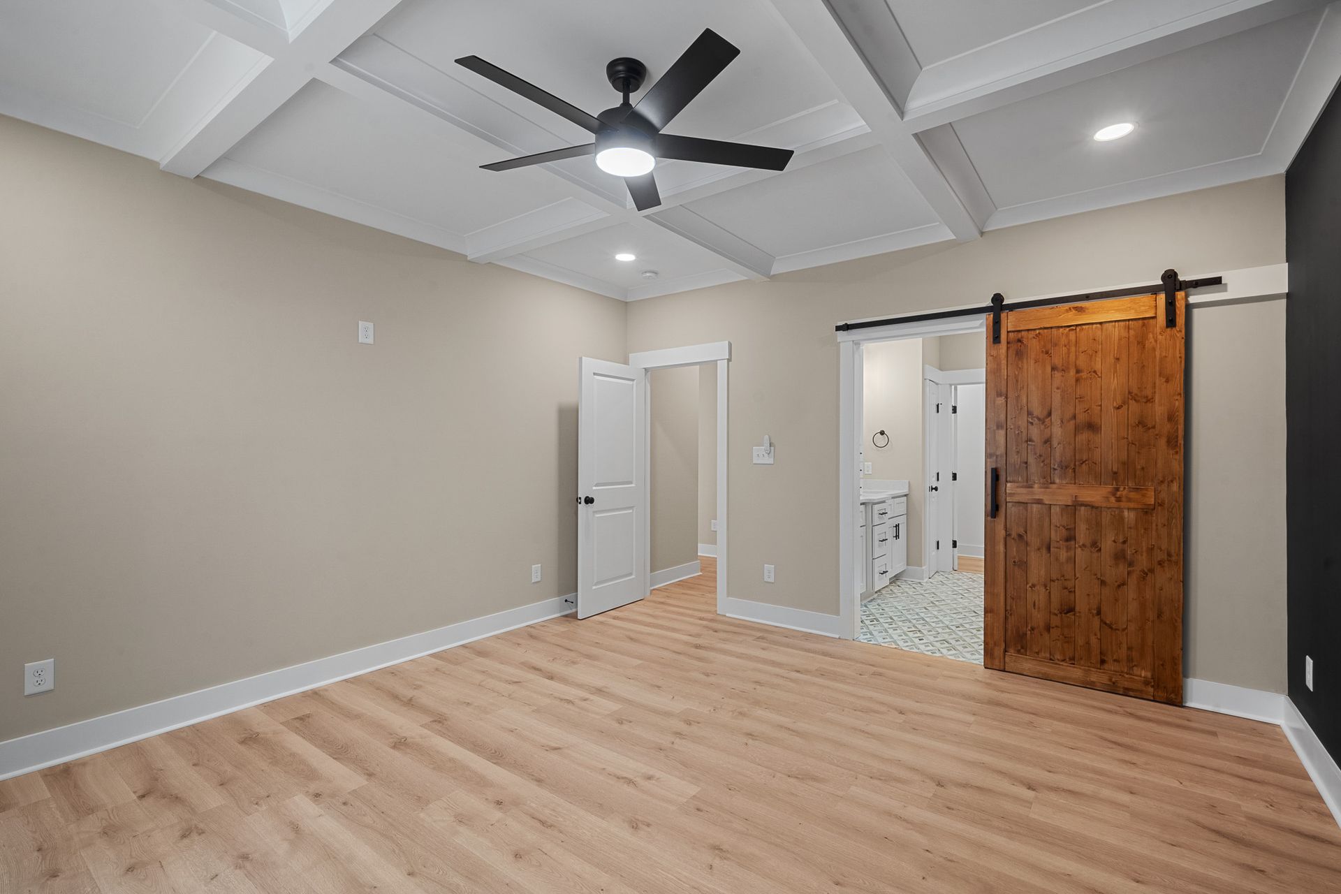 There is a ceiling fan in the room and a sliding barn door.