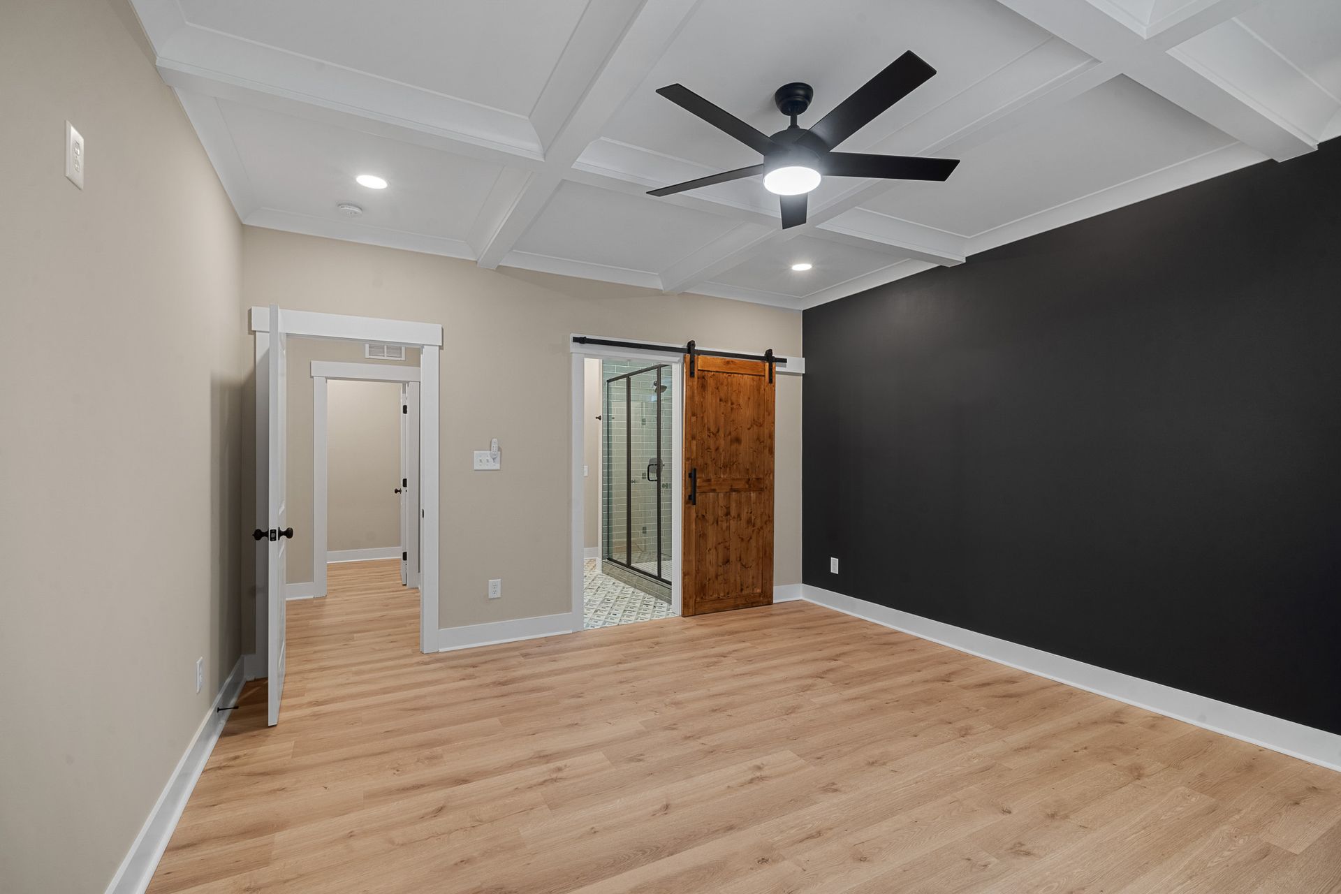 An empty room with a ceiling fan and a sliding barn door.