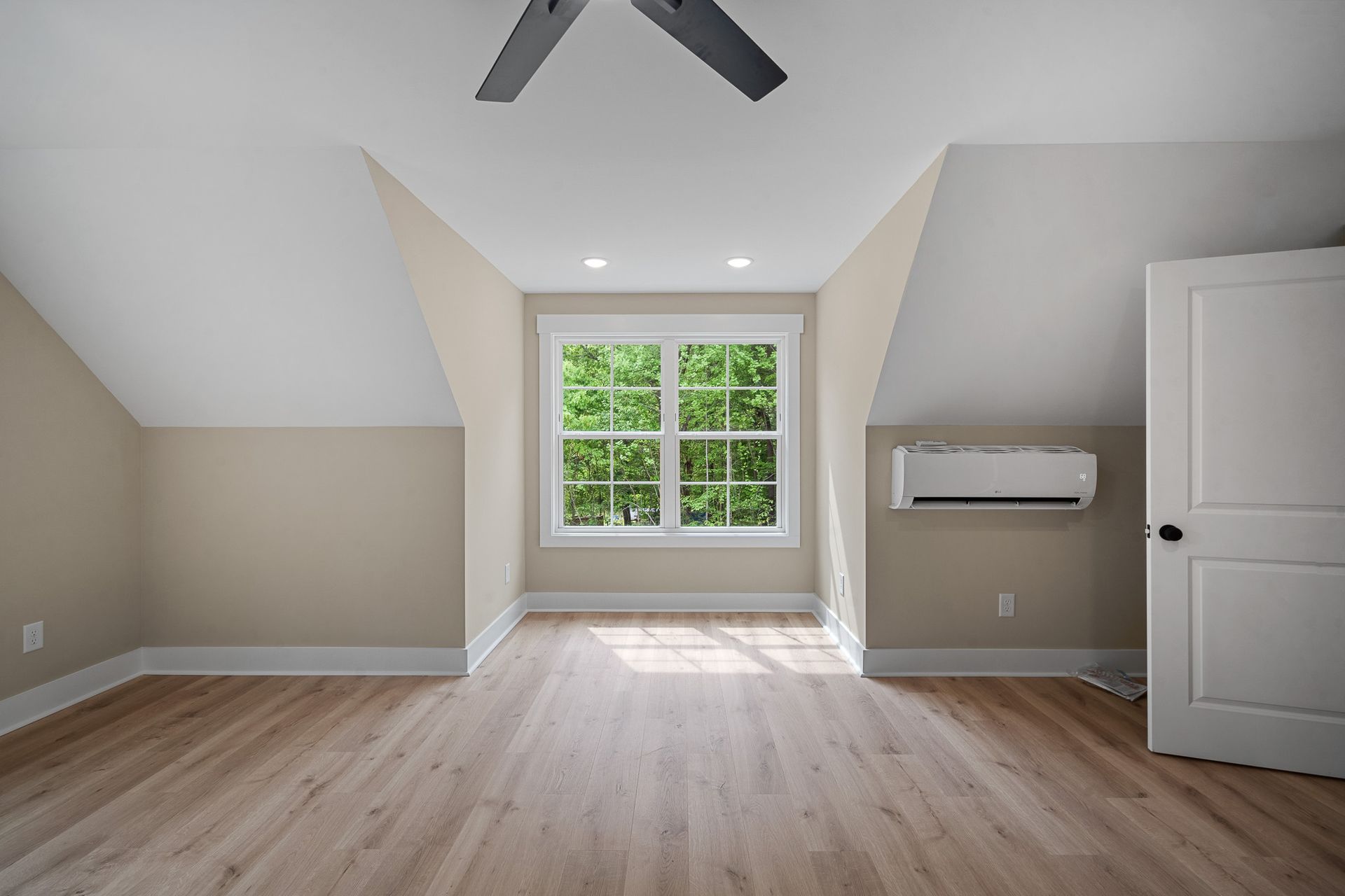 An empty room with a ceiling fan and a window