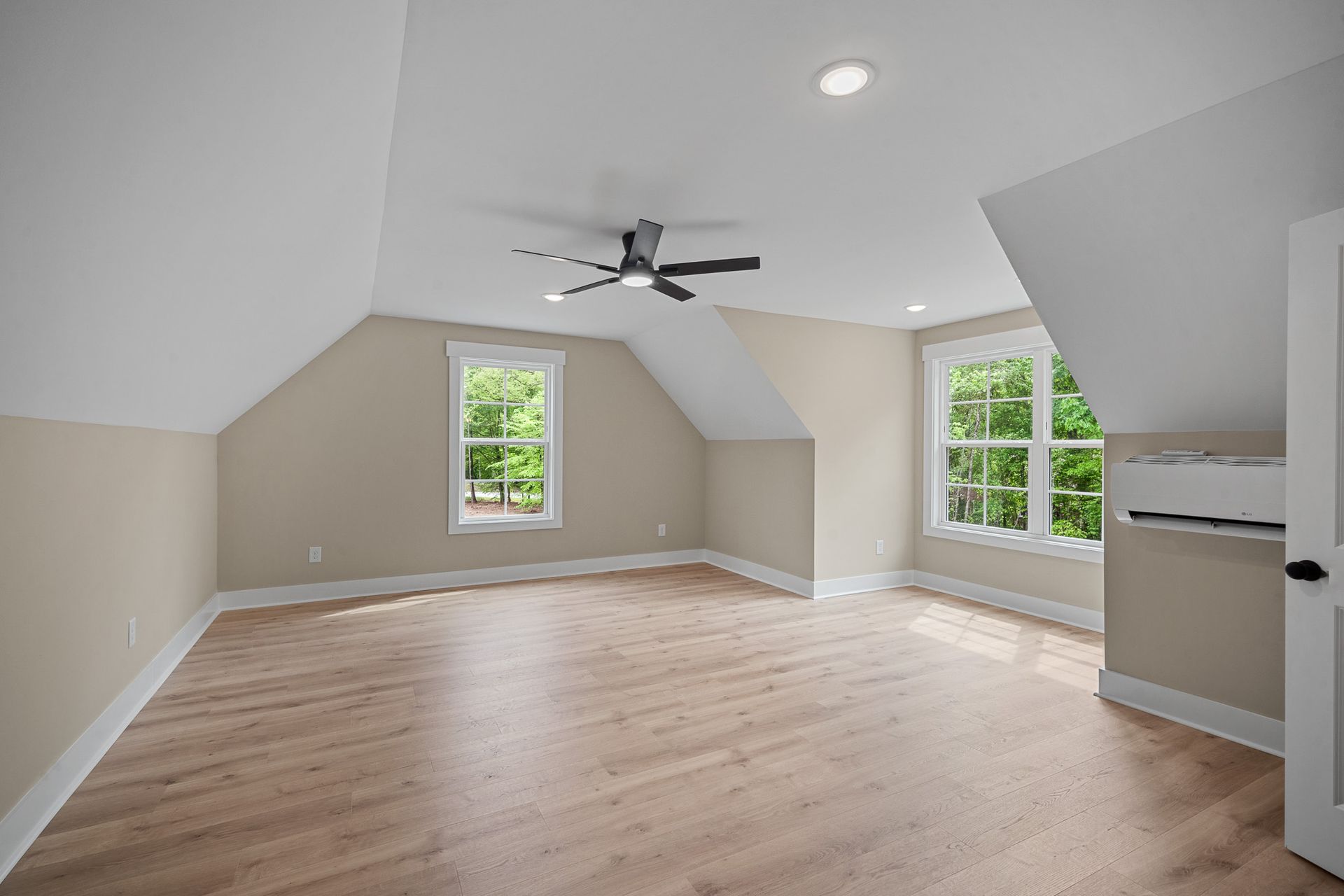 An empty room with hardwood floors and a ceiling fan.