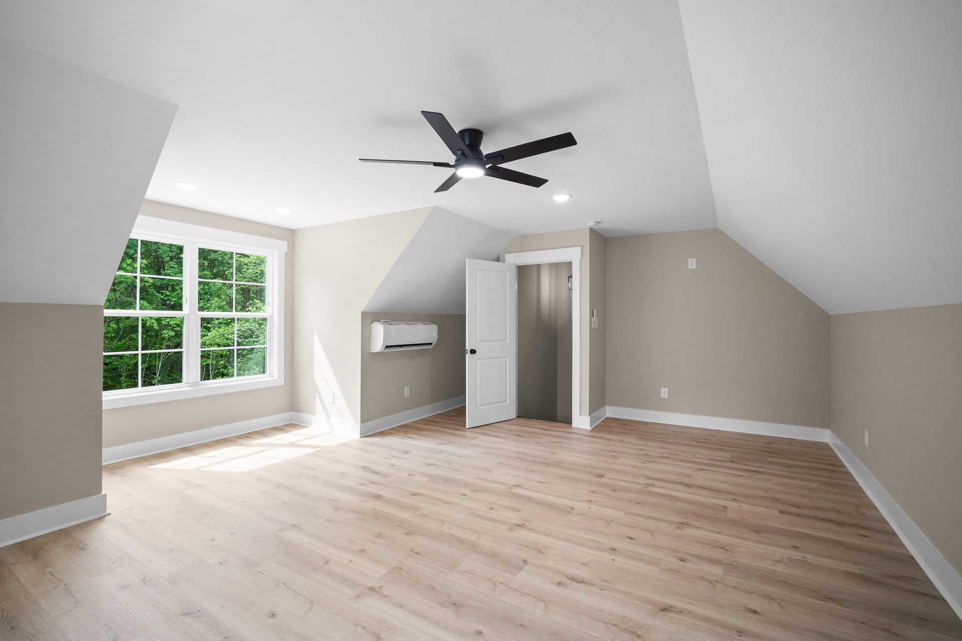 An empty room with a ceiling fan and a window.